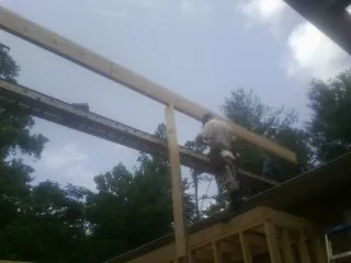 Carpenter setting a ridge beam over a new addition frame — Ice Dam Removal by Roofing Brothers in Louisburg