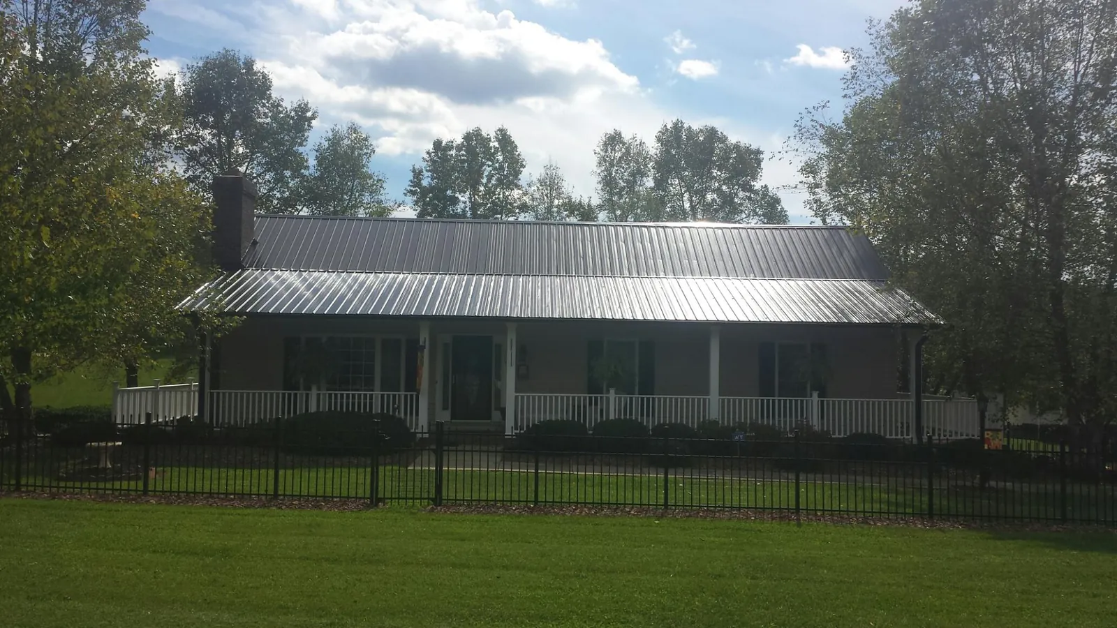 Gray metal roof on a brick ranch with a full width front porch — Gutter Guard Installation work by our crew in Louisburg